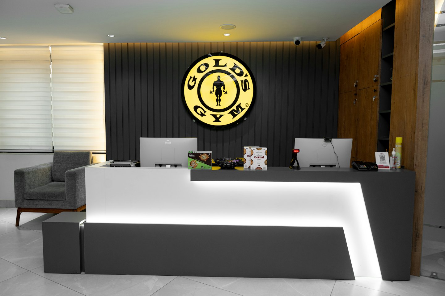 Modern gym reception desk with computer monitors and Gold's Gym logo.