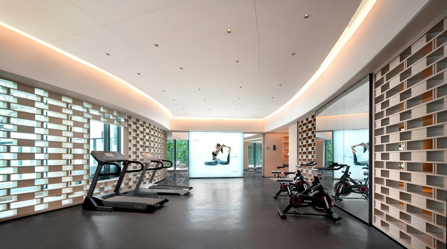 Bright modern gym with treadmills, bikes, and a yoga screen.